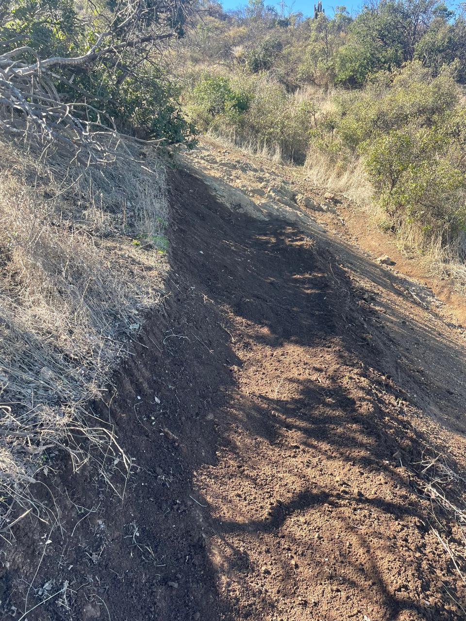 Tramo de sendero con la tierra recién movida y el talud reperfilado a mano
